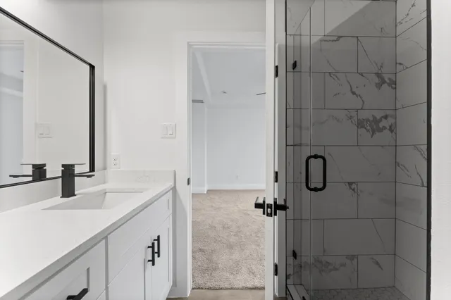 a bathroom with a sink vanity granite shower and a mirror
