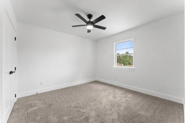an empty room with ceiling fan and windows
