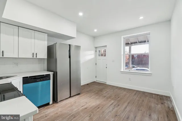 a kitchen with stainless steel appliances a refrigerator and a wooden floor