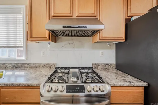 a kitchen with granite countertop a stove a sink and a white cabinets