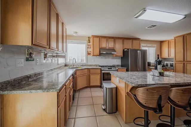 a kitchen with kitchen island granite countertop a stove top oven a sink a counter space and cabinets