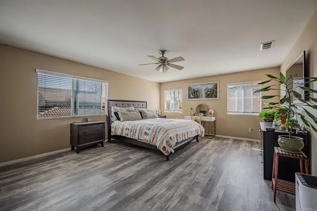 a spacious bedroom with a bed windows and a flat screen tv