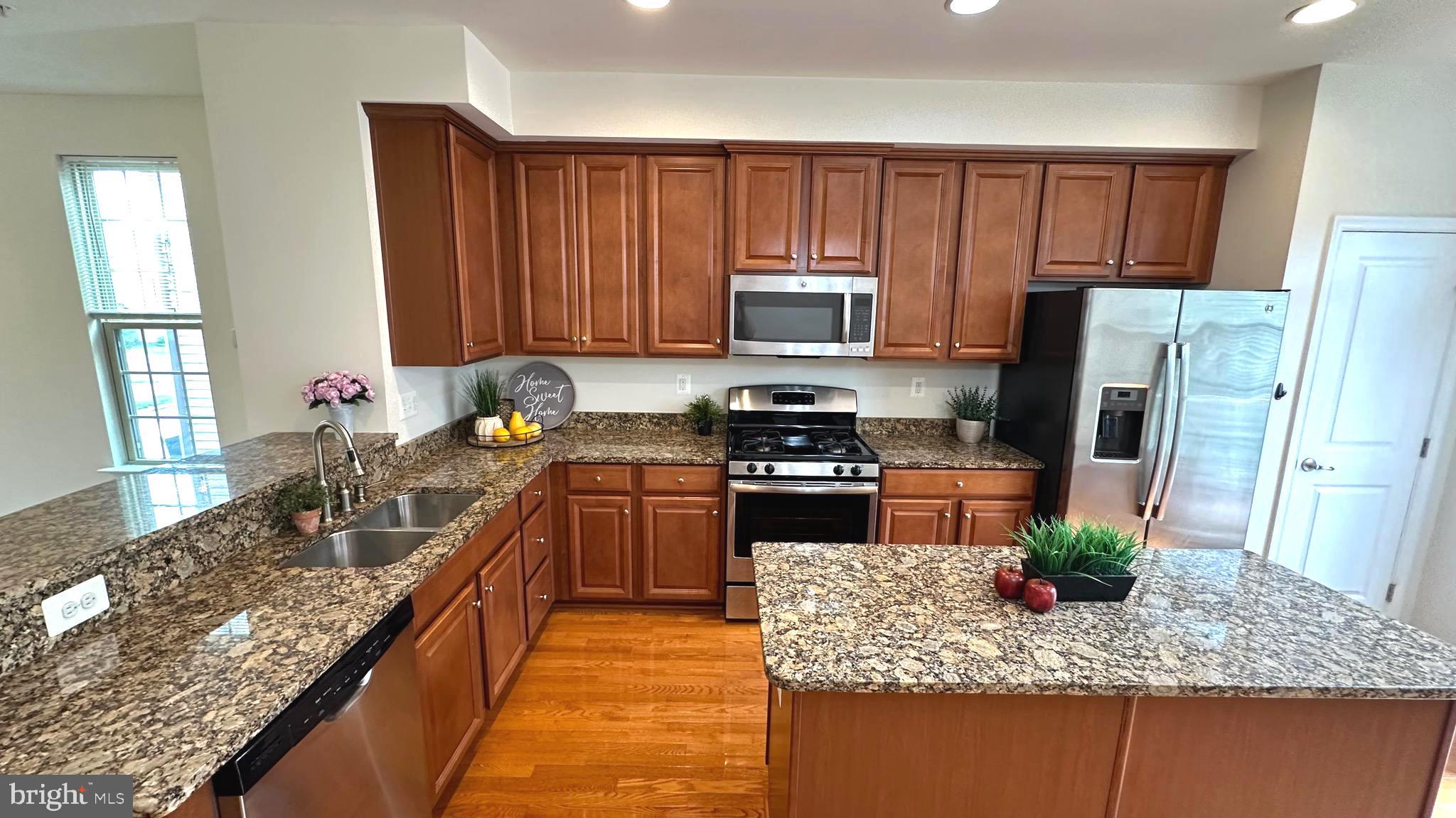 7343 Old Calvary Road Hanover, MD 21076 - Photo 15 of 35 a kitchen with kitchen island granite countertop a stove sink microwave and refrigerator