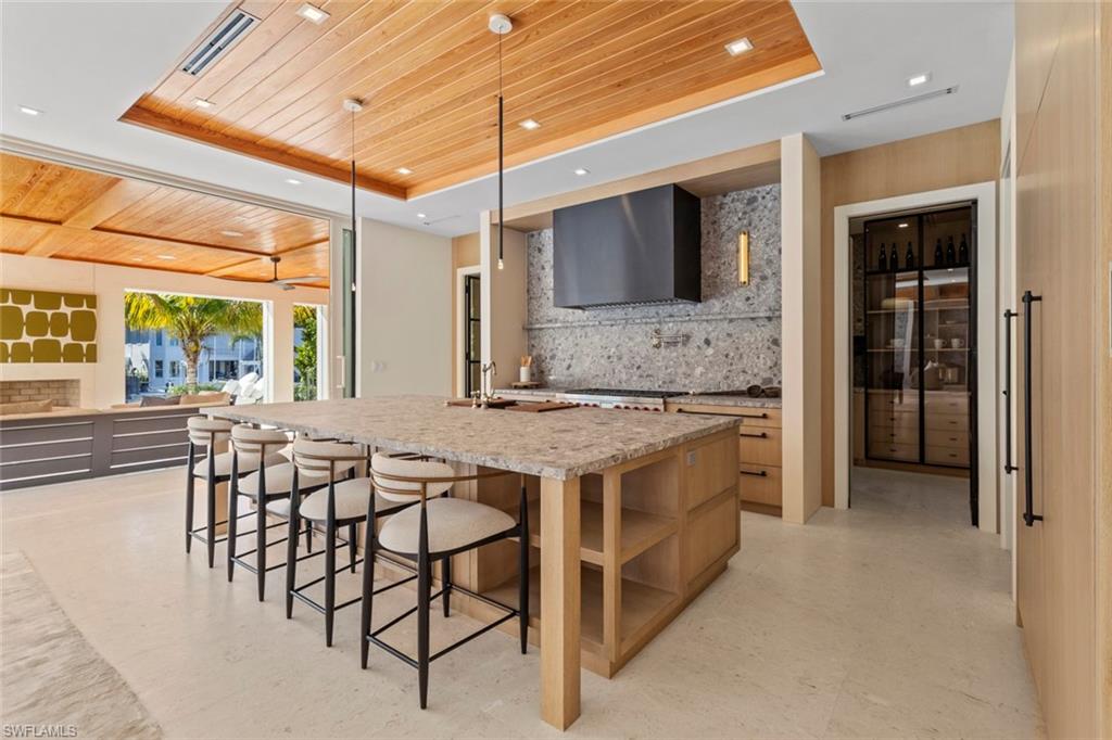 508 16th Avenue South Naples, FL 34102 - Photo 12 of 50 Kitchen featuring wooden ceiling, a raised ceiling, decorative backsplash, light stone countertops, and a large island with sink