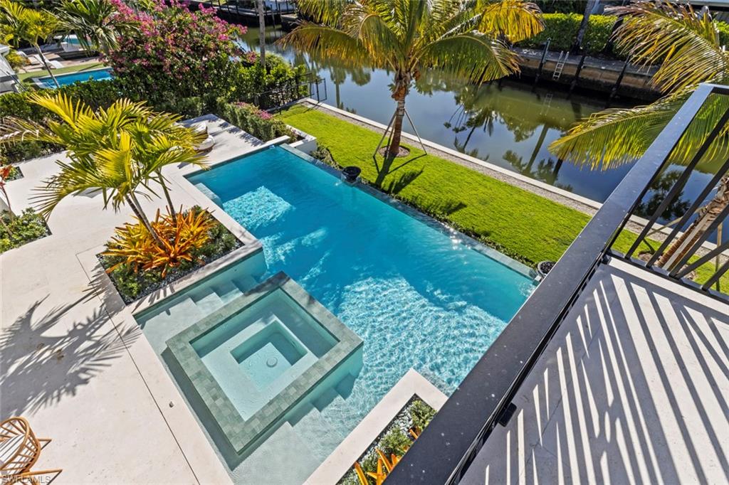 508 16th Avenue South Naples, FL 34102 - Photo 45 of 50 View of pool featuring a pool with connected hot tub, a water view, a yard, and a patio