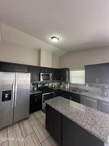 a large kitchen with stainless steel appliances granite countertop a stove a sink and a refrigerator