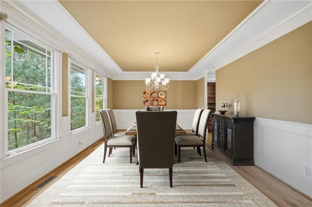 a kitchen with stainless steel appliances granite countertop wooden cabinets a sink dishwasher a stove and a dining table with wooden floor