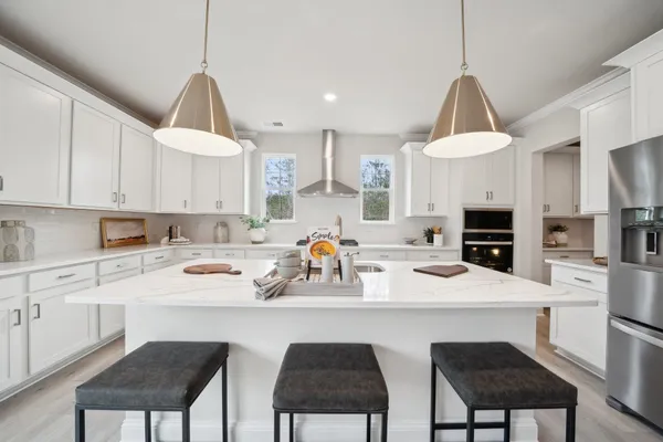 a kitchen with a sink a stove a refrigerator and white cabinets