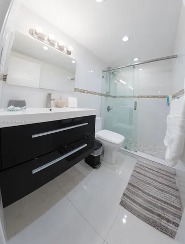 a bathroom with a sink a toilet a mirror and shower