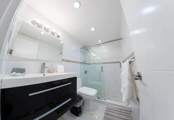 a bathroom with a sink a toilet a mirror and shower