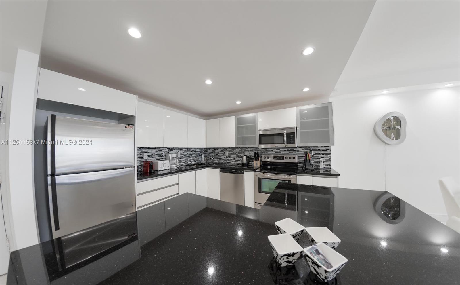 5601 Collins Avenue, Unit 1603 Miami Beach, FL 33140 - Photo 10 of 49 a kitchen with a sink stainless steel appliances and cabinets