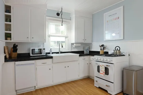 a kitchen with granite countertop white cabinets and white appliances