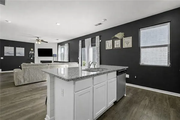 a kitchen with stainless steel appliances granite countertop a sink and a stove top oven with wooden floor