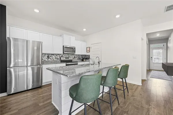 a kitchen with stainless steel appliances granite countertop a refrigerator a stove a sink dishwasher and a refrigerator with wooden floor