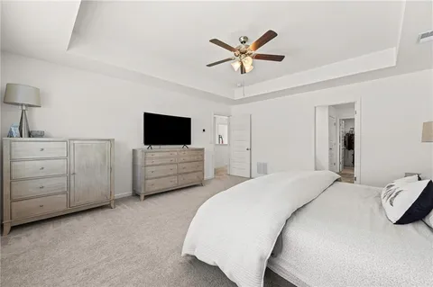 a spacious bedroom with a bed a chandelier and a television
