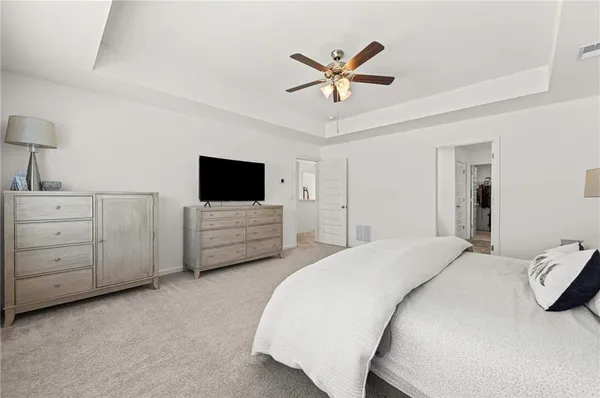 a spacious bedroom with a bed a chandelier and a television