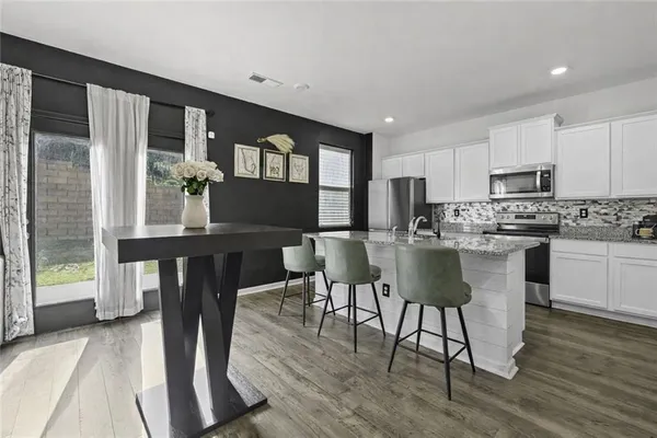 a kitchen with stainless steel appliances granite countertop a stove a refrigerator a kitchen island a table and chairs