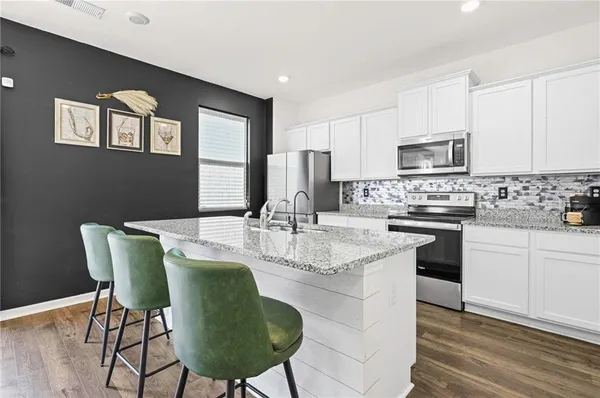 a kitchen with stainless steel appliances granite countertop a stove a sink a microwave a dining table and chairs