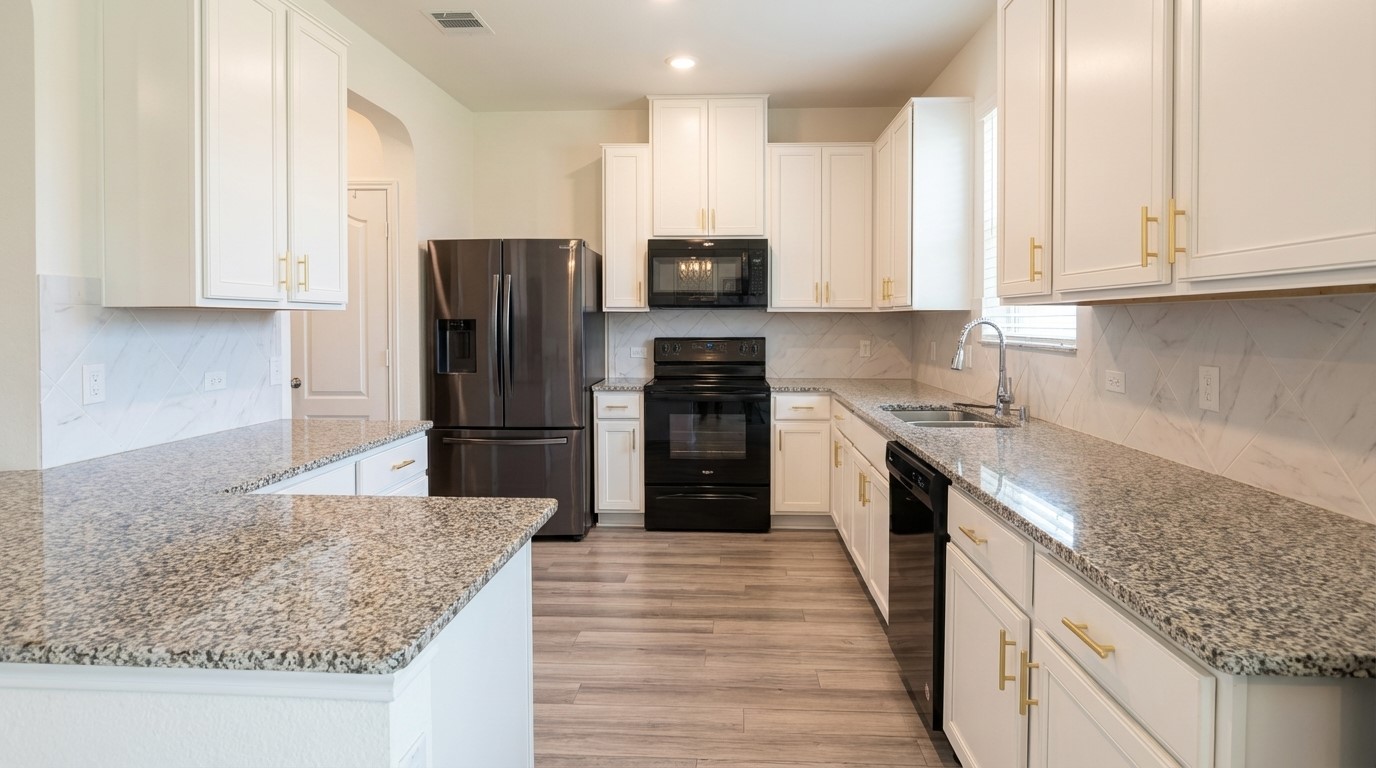 308 Los Cobos Lane Georgetown, TX 78626 - Photo 10 of 31 a kitchen with kitchen island granite countertop a stove oven and a refrigerator