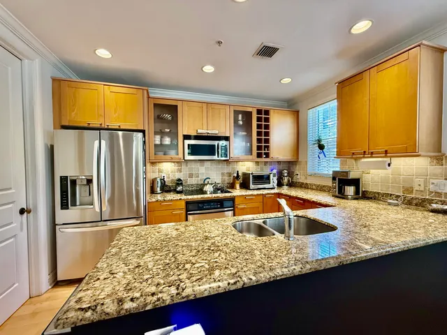 a kitchen with stainless steel appliances granite countertop sink stove refrigerator and cabinets