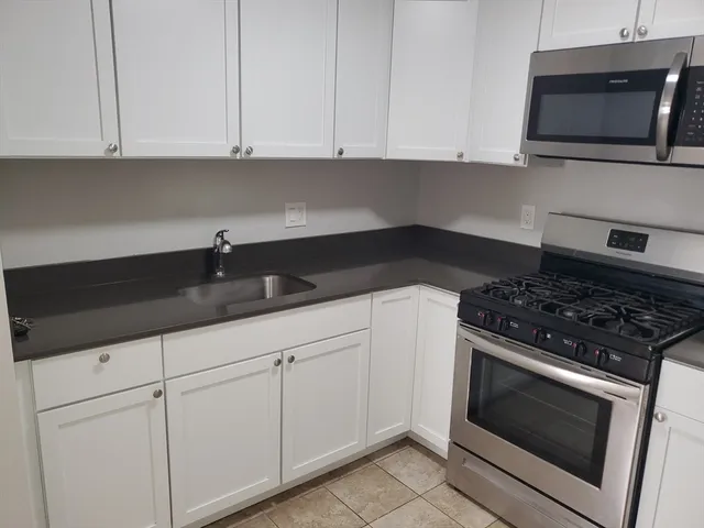 a kitchen with granite countertop white cabinets and stainless steel appliances