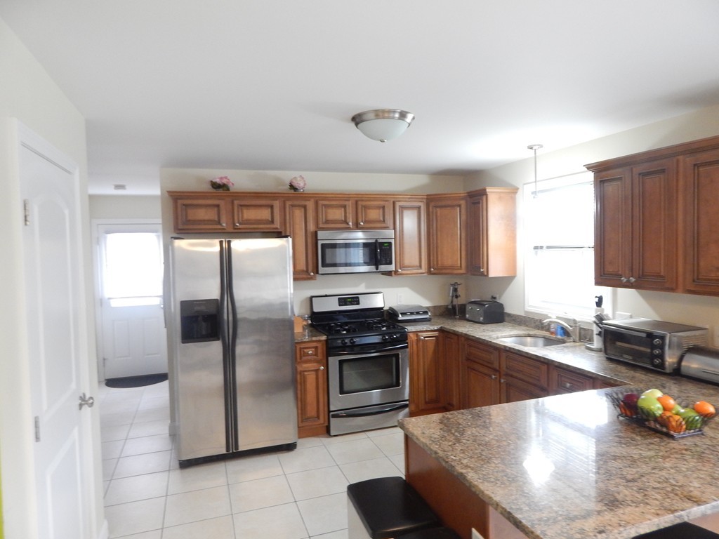 530 Stevens Street Fall River, MA 02721 - Photo 3 of 22 a kitchen with stainless steel appliances granite countertop a refrigerator a stove a sink a dining table and chairs
