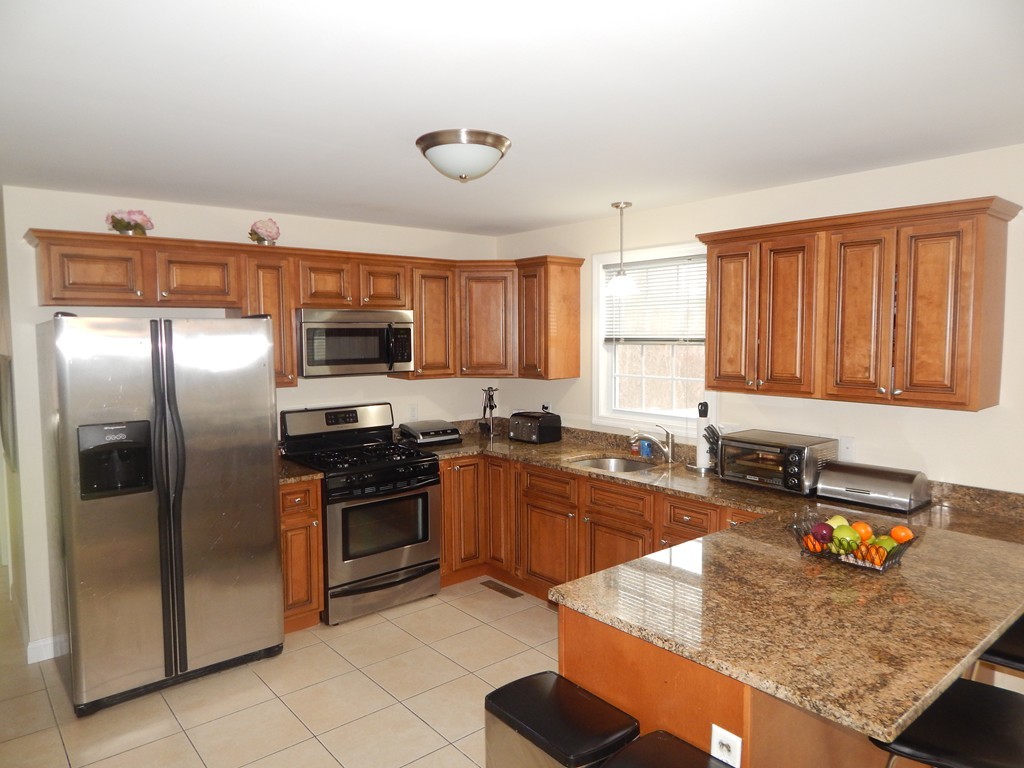 530 Stevens Street Fall River, MA 02721 - Photo 6 of 22 a kitchen with stainless steel appliances granite countertop a sink stove microwave and refrigerator