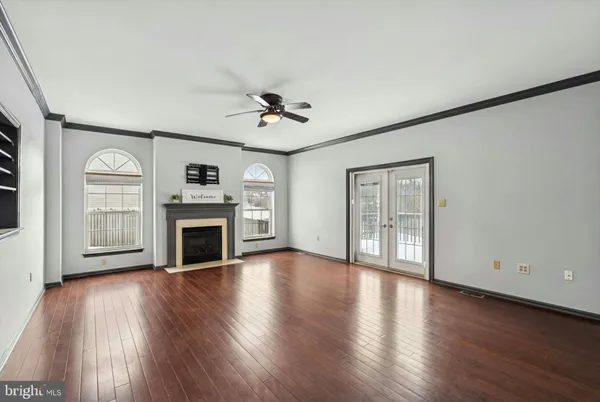 a view of a livingroom with wooden floor a ceiling fan and windows
