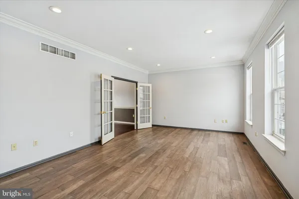 an empty room with wooden floor and windows