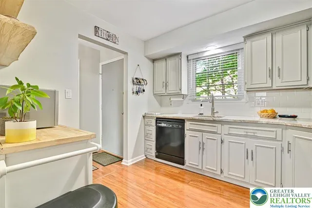 a kitchen with stainless steel appliances a sink a stove a refrigerator cabinets and a window