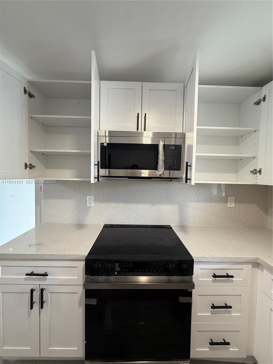 1055 Northwest 34th Avenue, Unit 1055 Miami, FL 33125 - Photo 8 of 19 a kitchen with a stove and a cabinet
