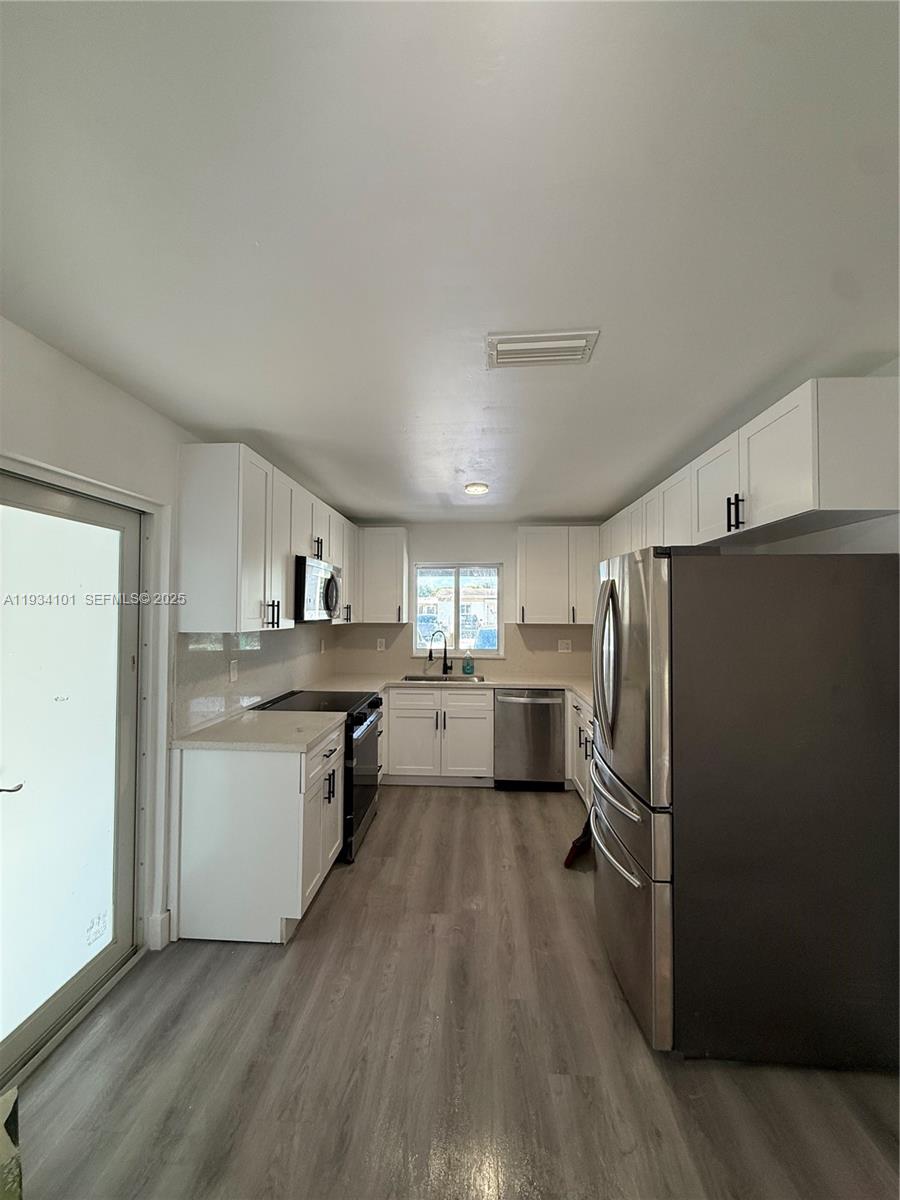 1055 Northwest 34th Avenue, Unit 1055 Miami, FL 33125 - Photo 9 of 19 a kitchen with refrigerator cabinets and wooden floor