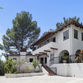 a view of a white house with a large tree and plants