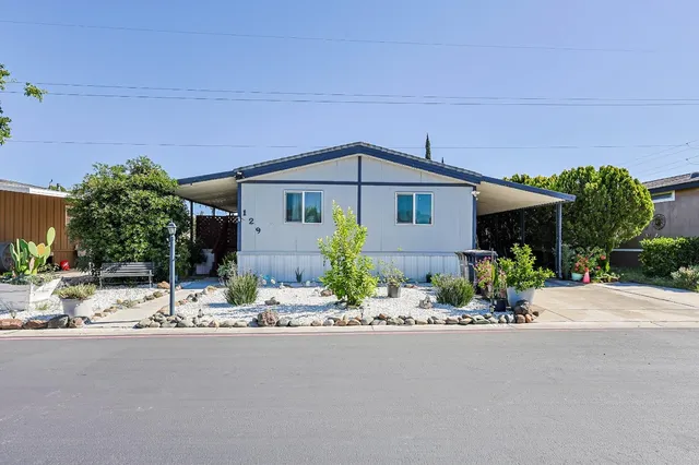 a front view of a house with a garden and mountain view