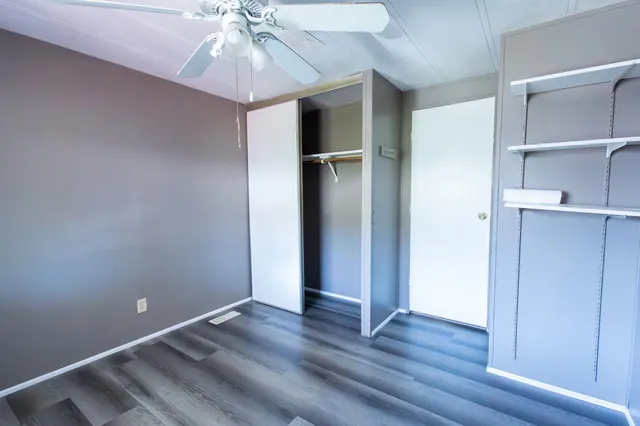 an empty room with wooden floor closet and windows