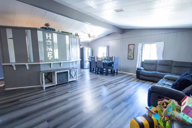 a living room with furniture a dining table wooden floor and a large window