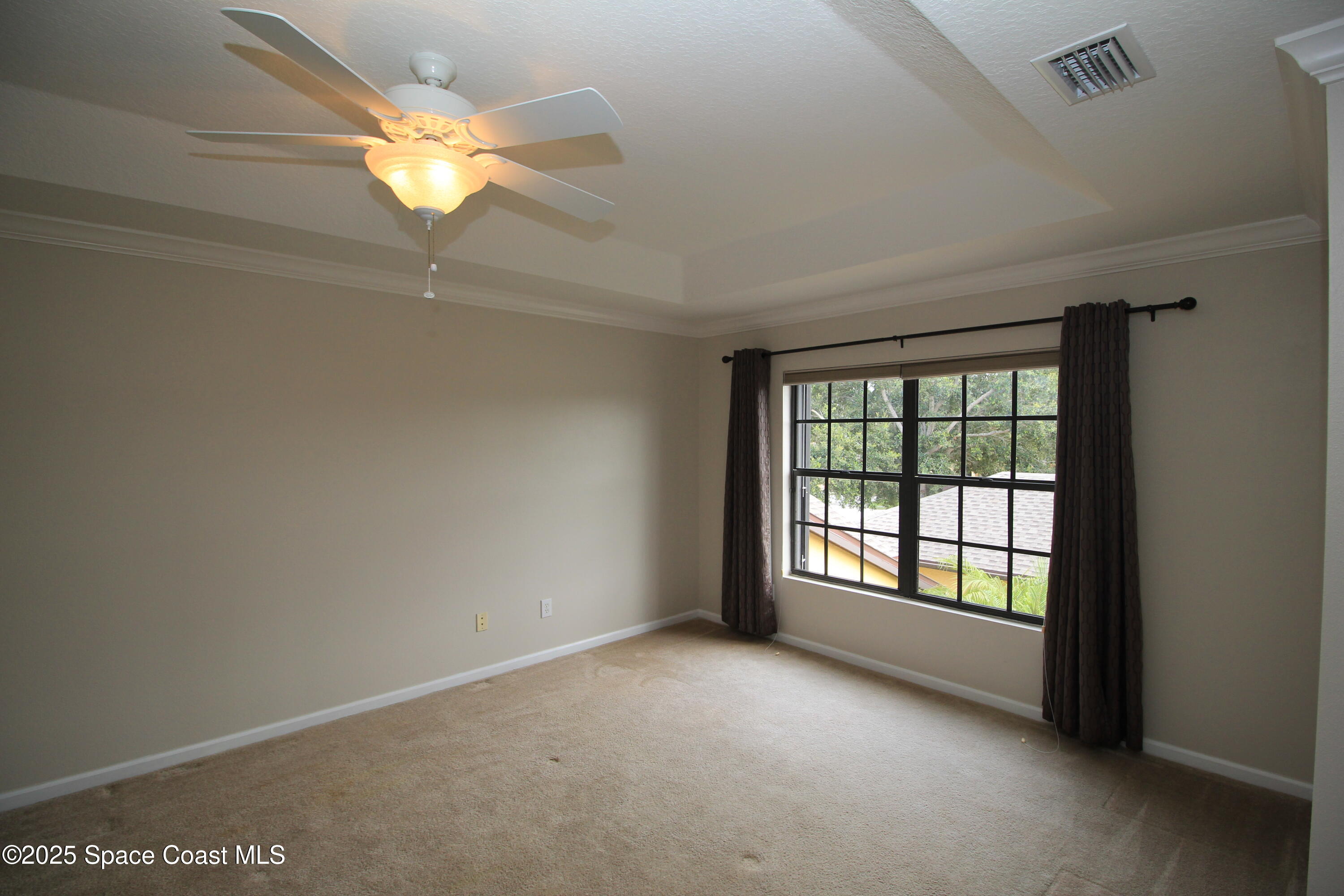 1075 Luminary Circle, Unit 102 Melbourne, FL 32901 - Photo 13 of 18 an empty room with a chandelier fan and windows