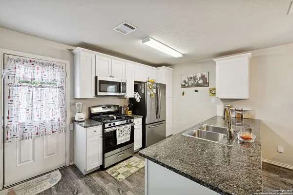 a kitchen with granite countertop a sink a stove and cabinets
