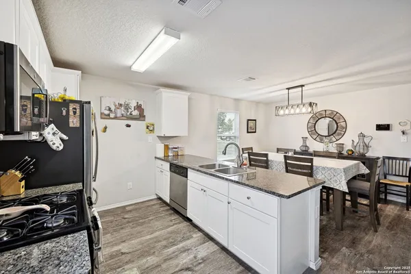a kitchen with stainless steel appliances granite countertop a sink stove refrigerator and cabinets