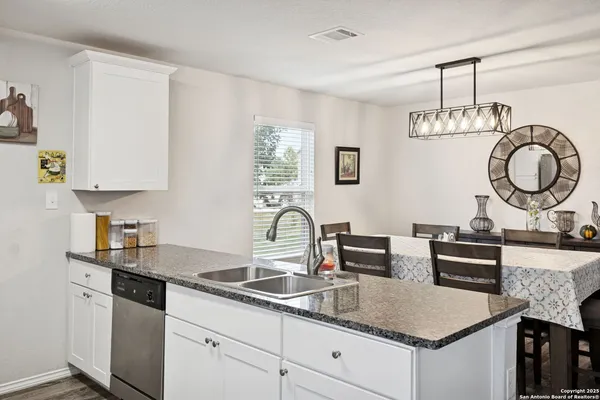 a kitchen with granite countertop a sink dishwasher stove and cabinets