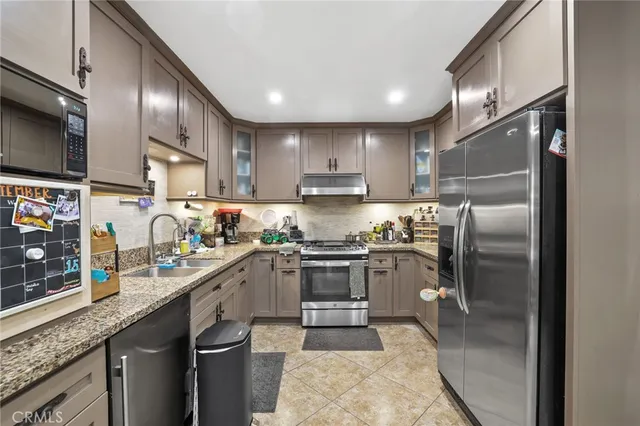 a kitchen with stainless steel appliances granite countertop a sink refrigerator and cabinets
