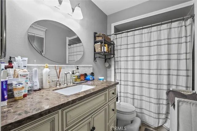 a bathroom with a granite countertop sink mirror vanity and toilet
