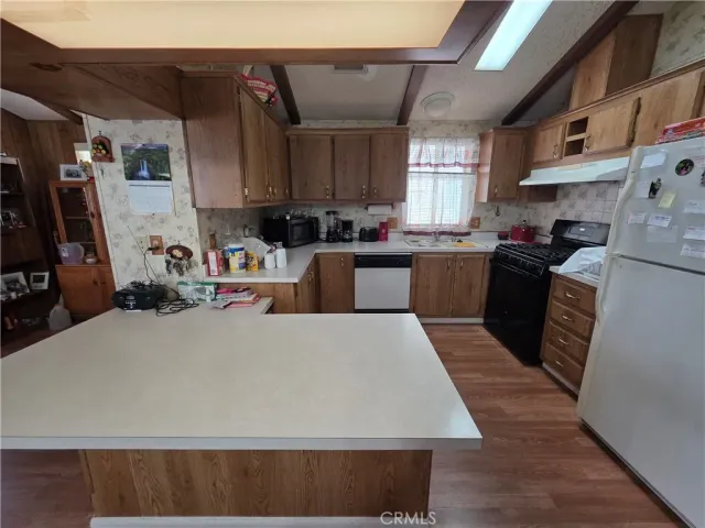 a kitchen with kitchen island a counter top space a sink a stove and wooden floor