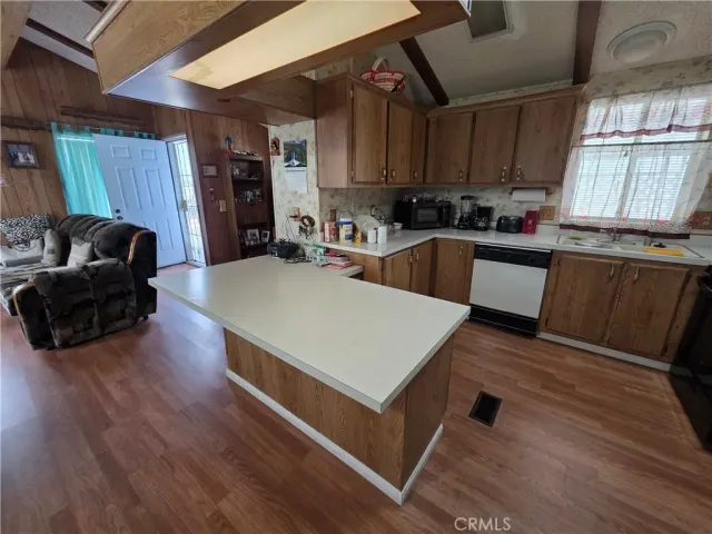 a kitchen with stainless steel appliances granite countertop a refrigerator a sink dishwasher a stove and white countertops with wooden floor