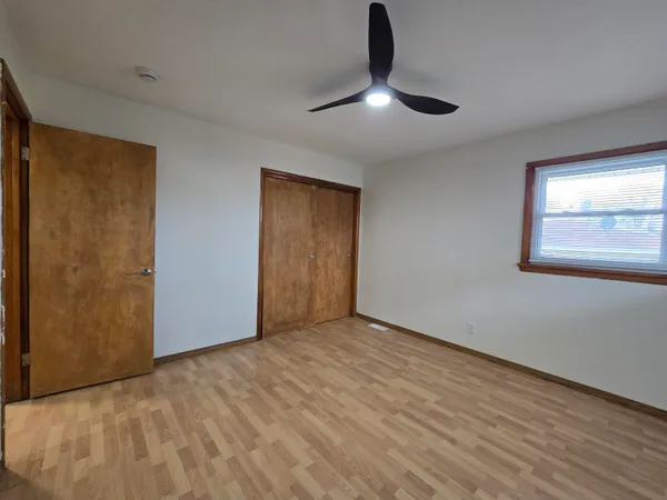 a view of an empty room with window and chandelier fan