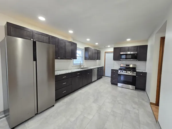 a kitchen with stainless steel appliances kitchen island granite countertop a refrigerator and a stove top oven