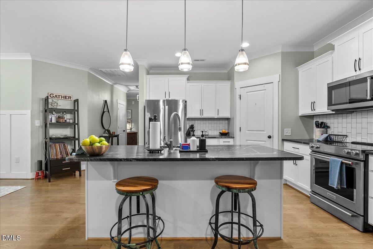 47 Kiowa Court Willow Spring, NC 27592 - Photo 3 of 30 a kitchen with stainless steel appliances a stove a sink and chairs with wooden floor