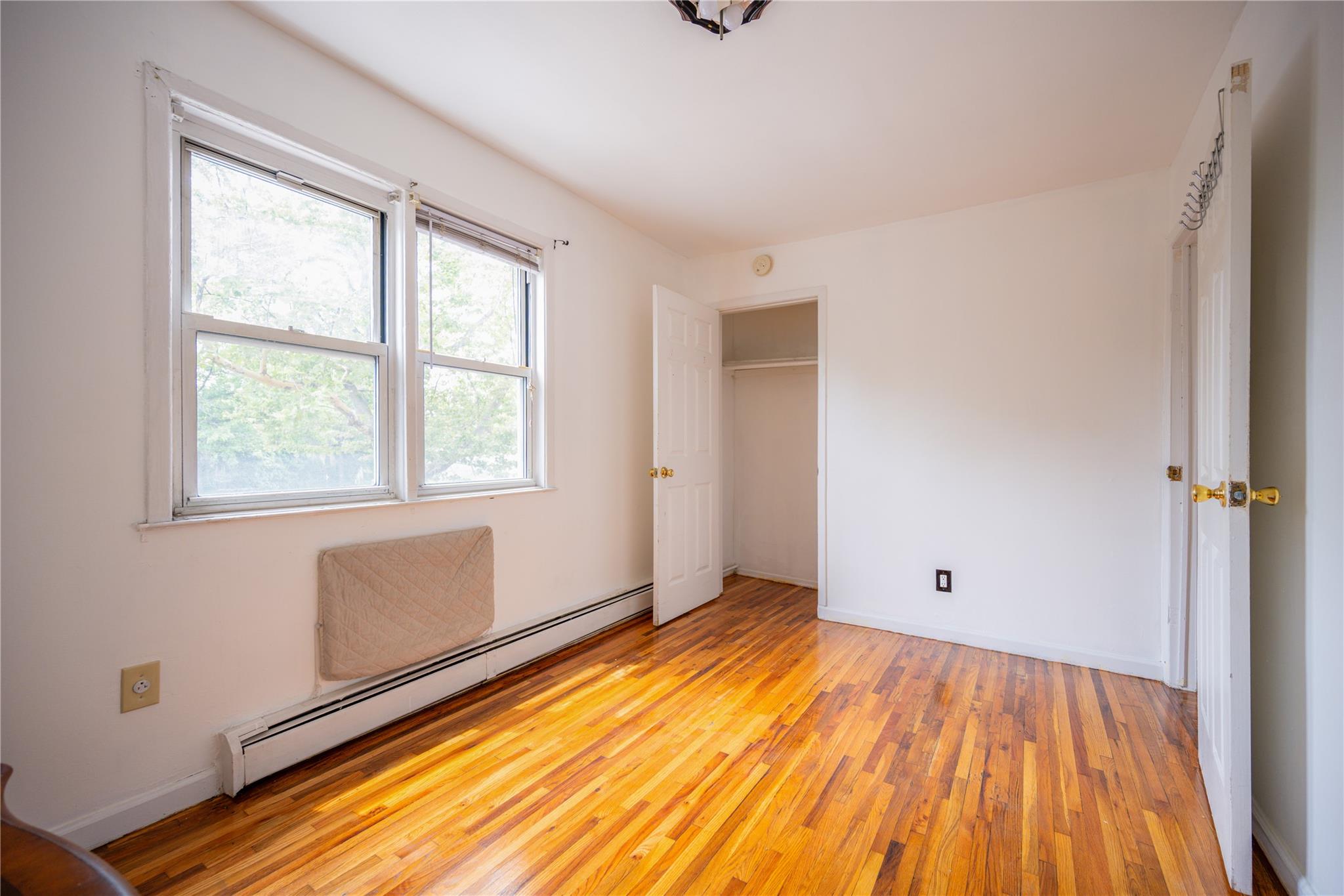 59-38 Xenia Street Queens, NY 11368 - Photo 11 of 16 a view of an empty room with wooden floor and a window