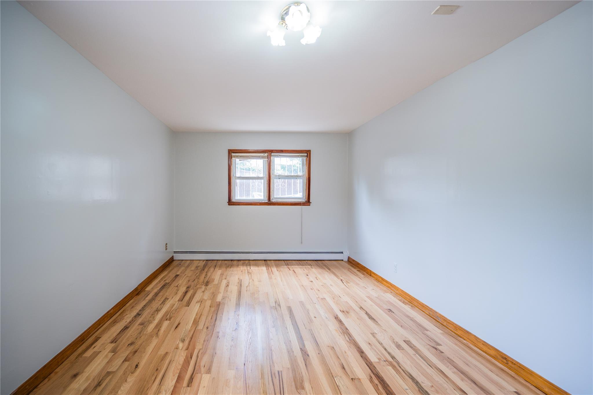 59-38 Xenia Street Queens, NY 11368 - Photo 14 of 16 a view of an empty room with wooden floor and a window