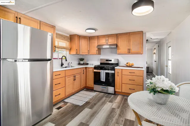 a kitchen with granite countertop a white refrigerator a sink dishwasher and white cabinets with wooden floor